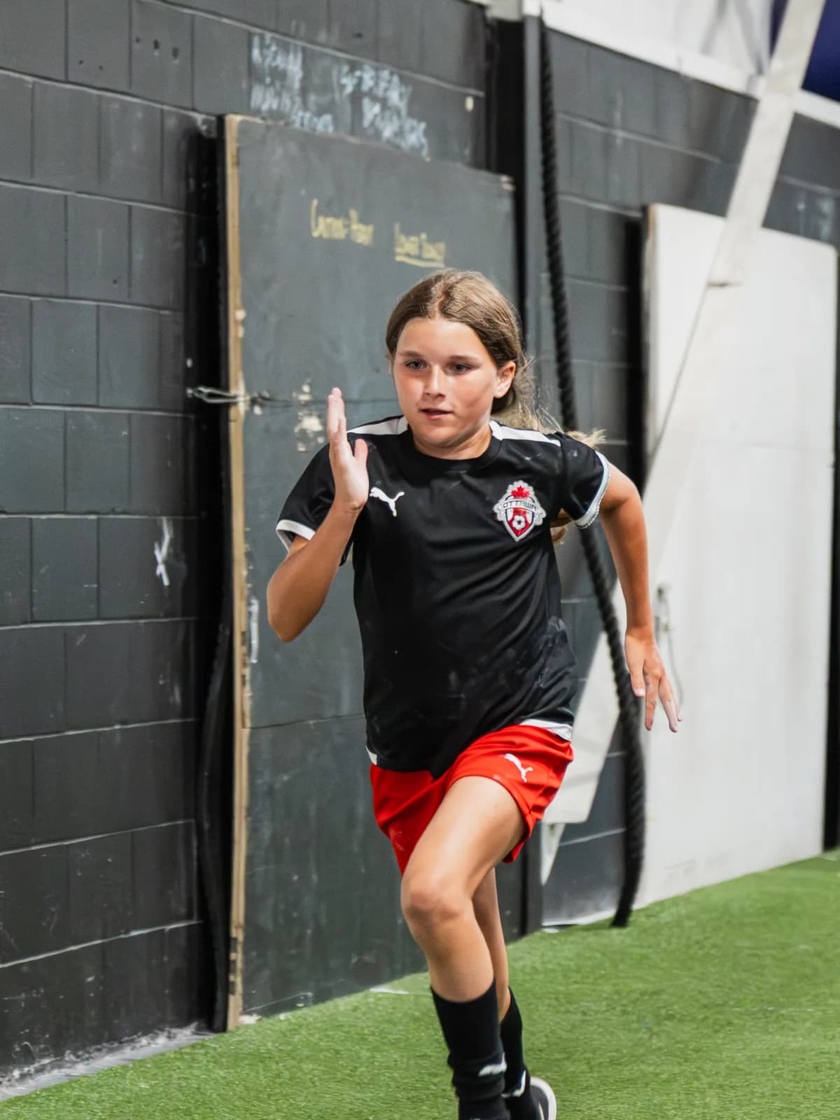 A youth athlete practising sprint mechanics on the CANAM turf